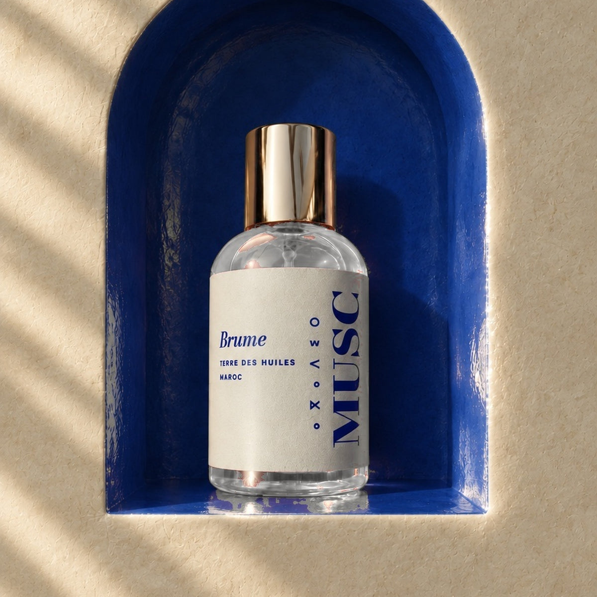 Flacon Brume Musc Terre Des Huiles 30 ml dans une niche bleu roi, mur de tadelakt au soleil